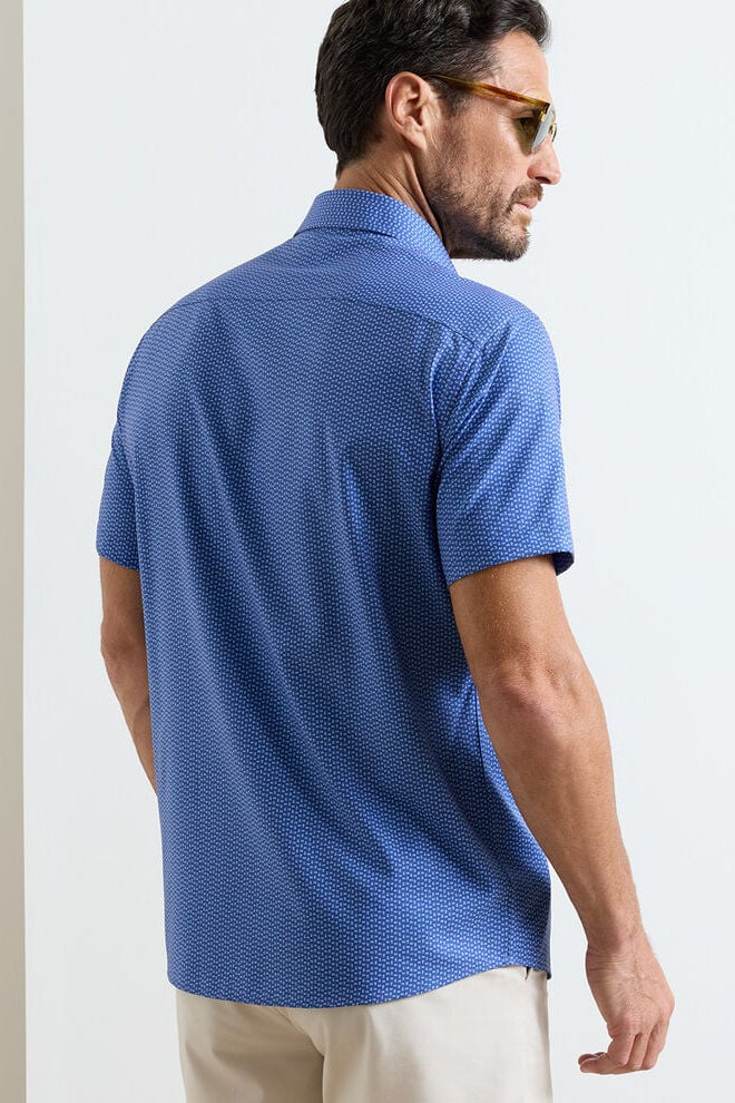Man wearing a blue patterned polo shirt on a plain background