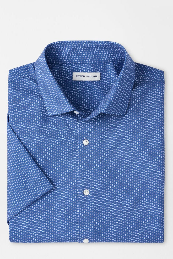 Folded blue patterned shirt with 'Peter Millar' label on a light gray background