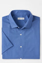Folded blue patterned shirt with 'Peter Millar' label on a light gray background