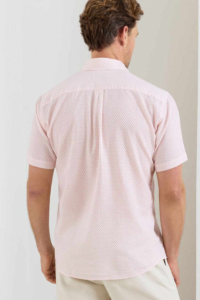 Man wearing a pink patterned shirt against a plain background