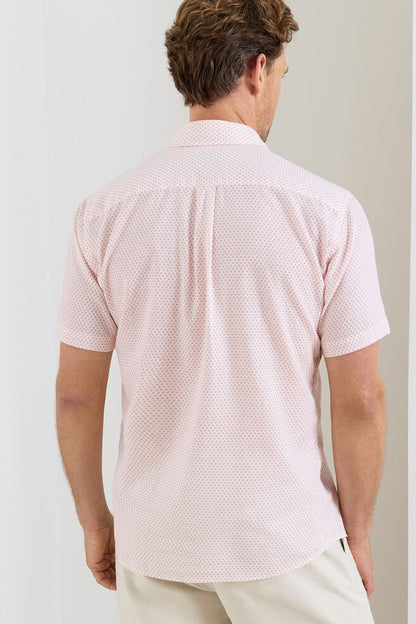 Man wearing a pink patterned shirt against a plain background