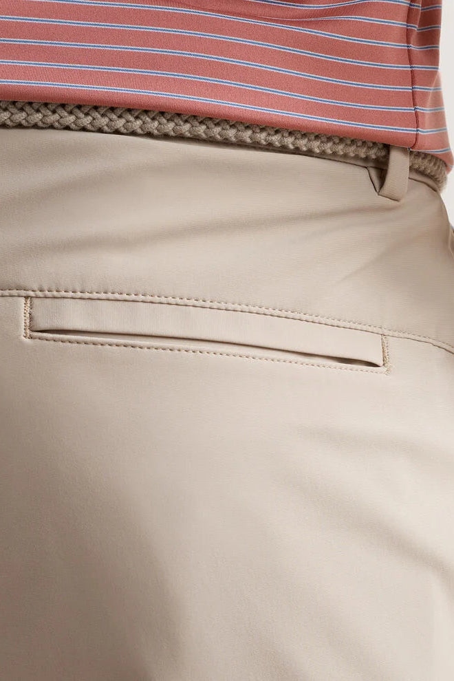 Close-up of beige pants with a striped shirt in the background