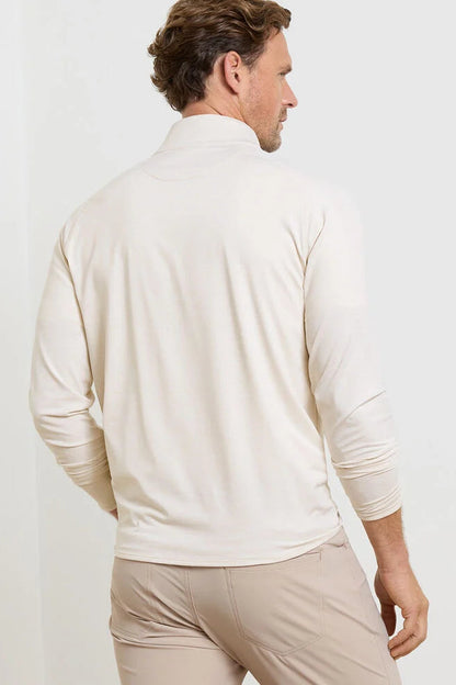Man wearing a beige long-sleeve shirt and pants against a white background