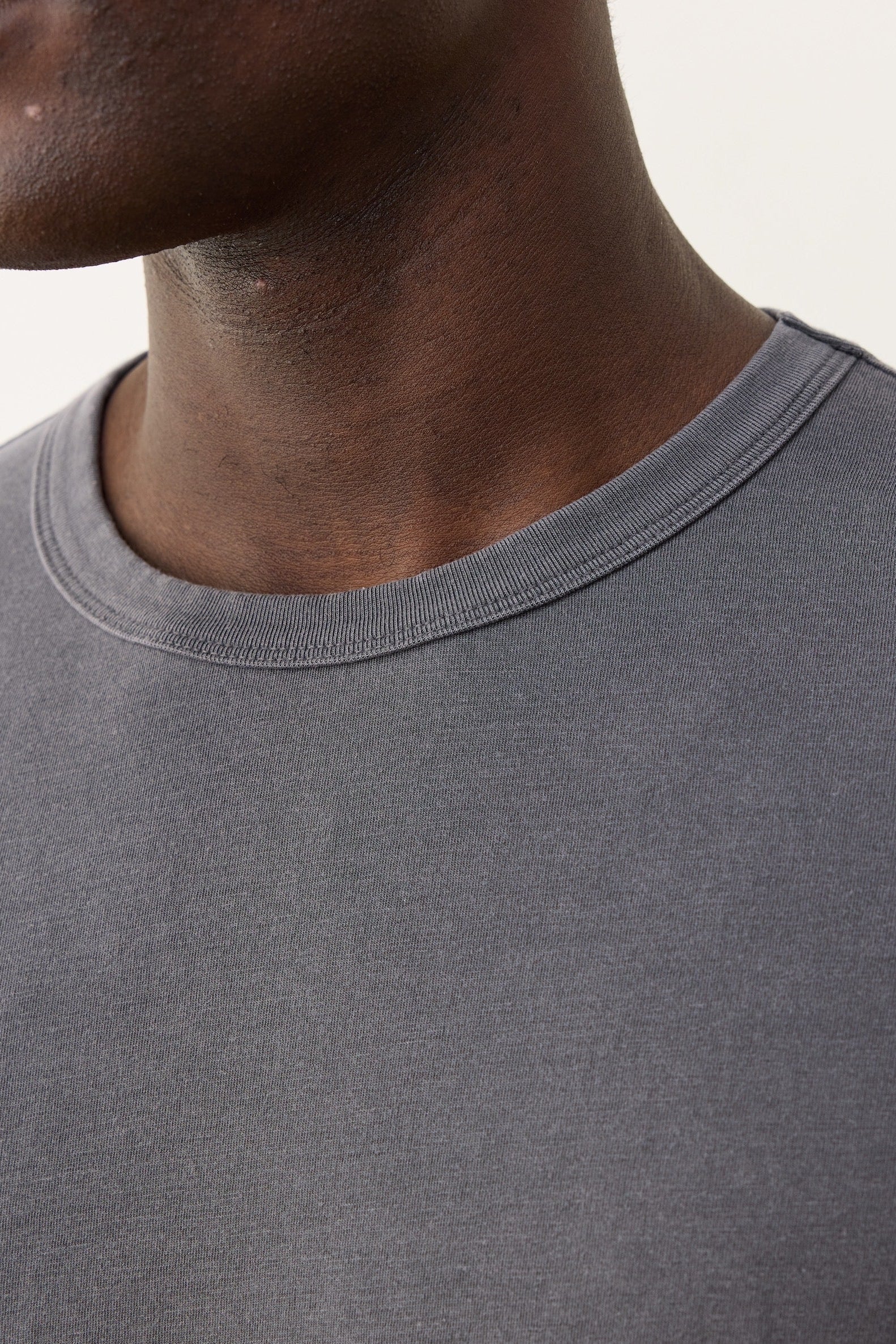 Close-up of a person wearing a gray t-shirt with a neutral background