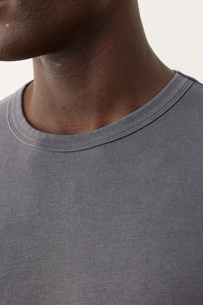 Close-up of a person wearing a gray t-shirt with a neutral background