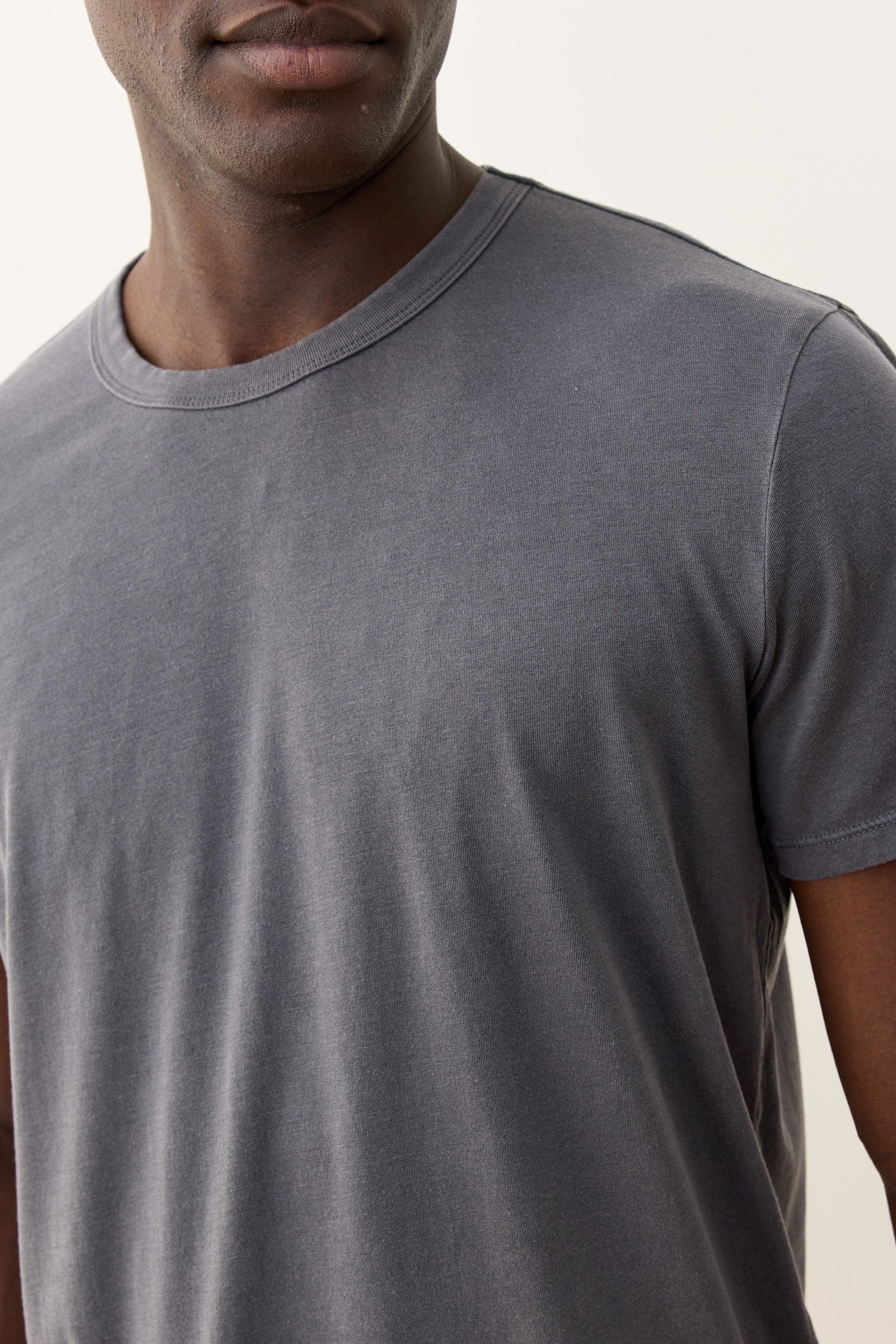 Person wearing a plain gray t-shirt against a neutral background
