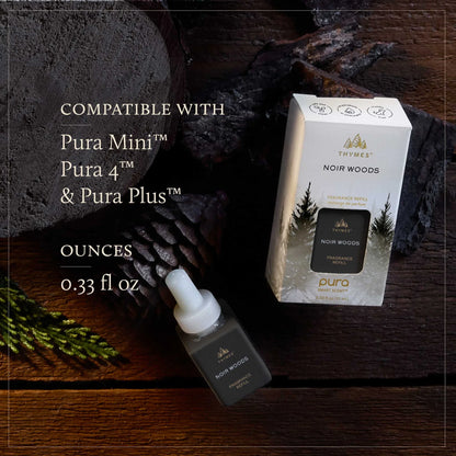 Thymes Noir Woods fragrance refill bottle and packaging on a wooden surface with text indicating compatibility.