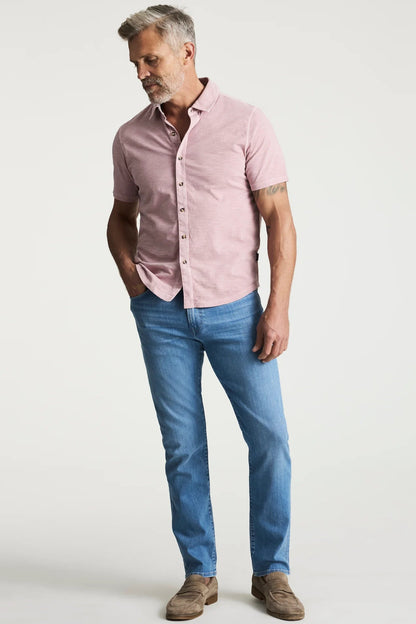 Man wearing a pink shirt and blue jeans on a white background