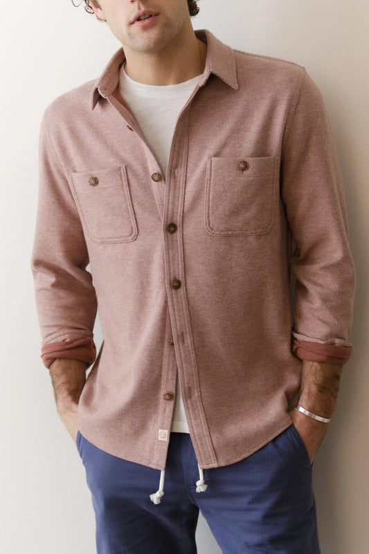 man wearing faded red overshirt against white background
