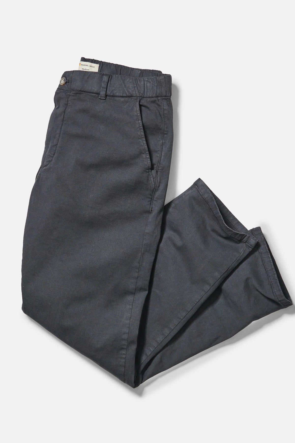 Dark charcoal gray trousers folded neatly on a light gray background.