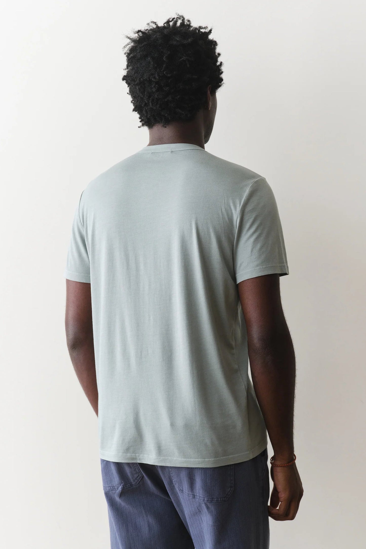 Person wearing a light green t-shirt and blue pants against a white background