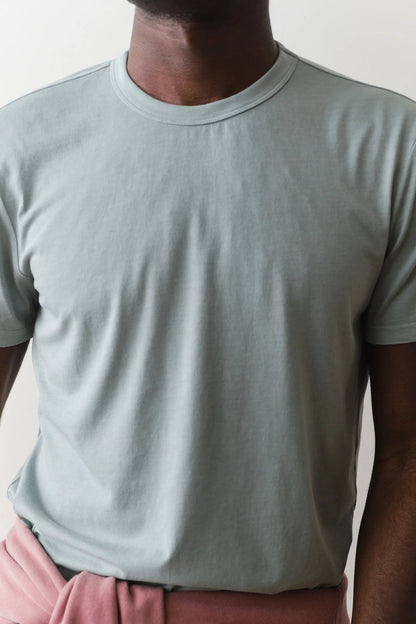 Person wearing a light gray t-shirt and pink pants against a plain background