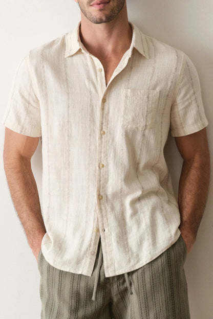 Man wearing a beige short-sleeve shirt against a plain background