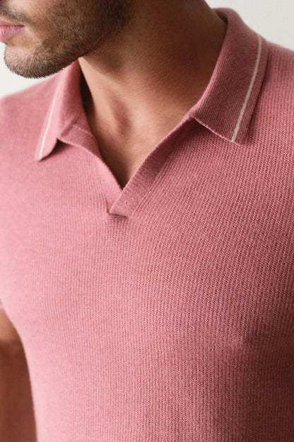Close-up of a person wearing a pink polo shirt with a neutral background