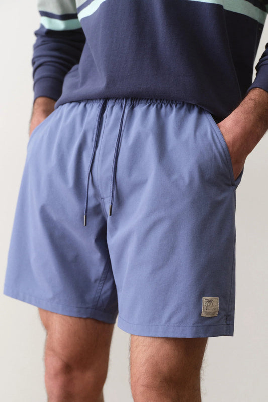 Person wearing blue shorts with a visible brand logo on a plain background