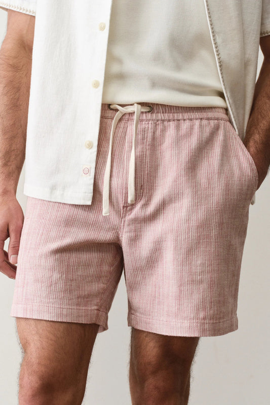 Person wearing pink checkered shorts with a neutral background