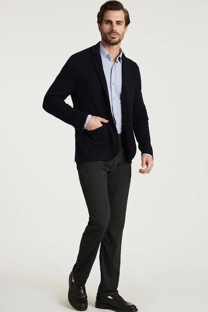 Man wearing a dark blazer, light shirt, and dark pants on a white background