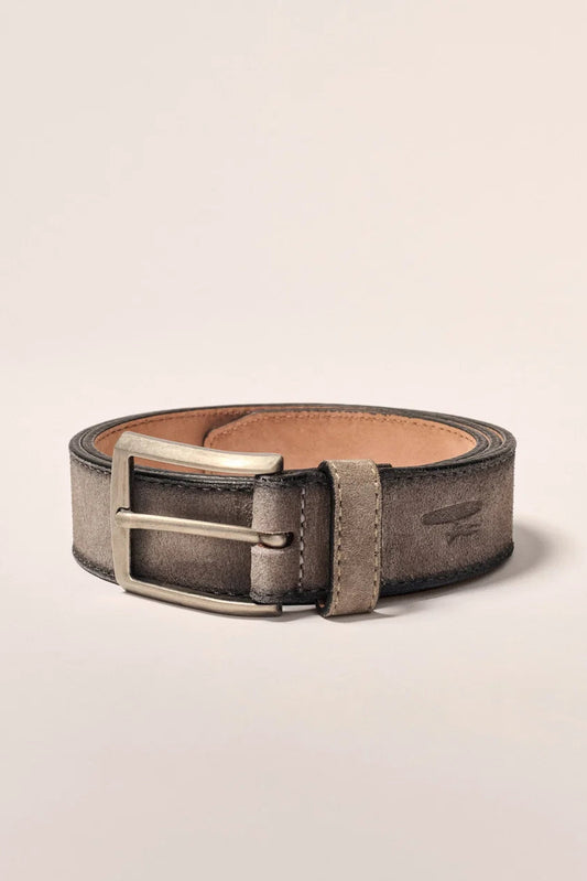 A rolled-up leather belt in a distressed gray finish with a silver-tone metal buckle and a light tan interior lining, photographed on a clean, light beige background.