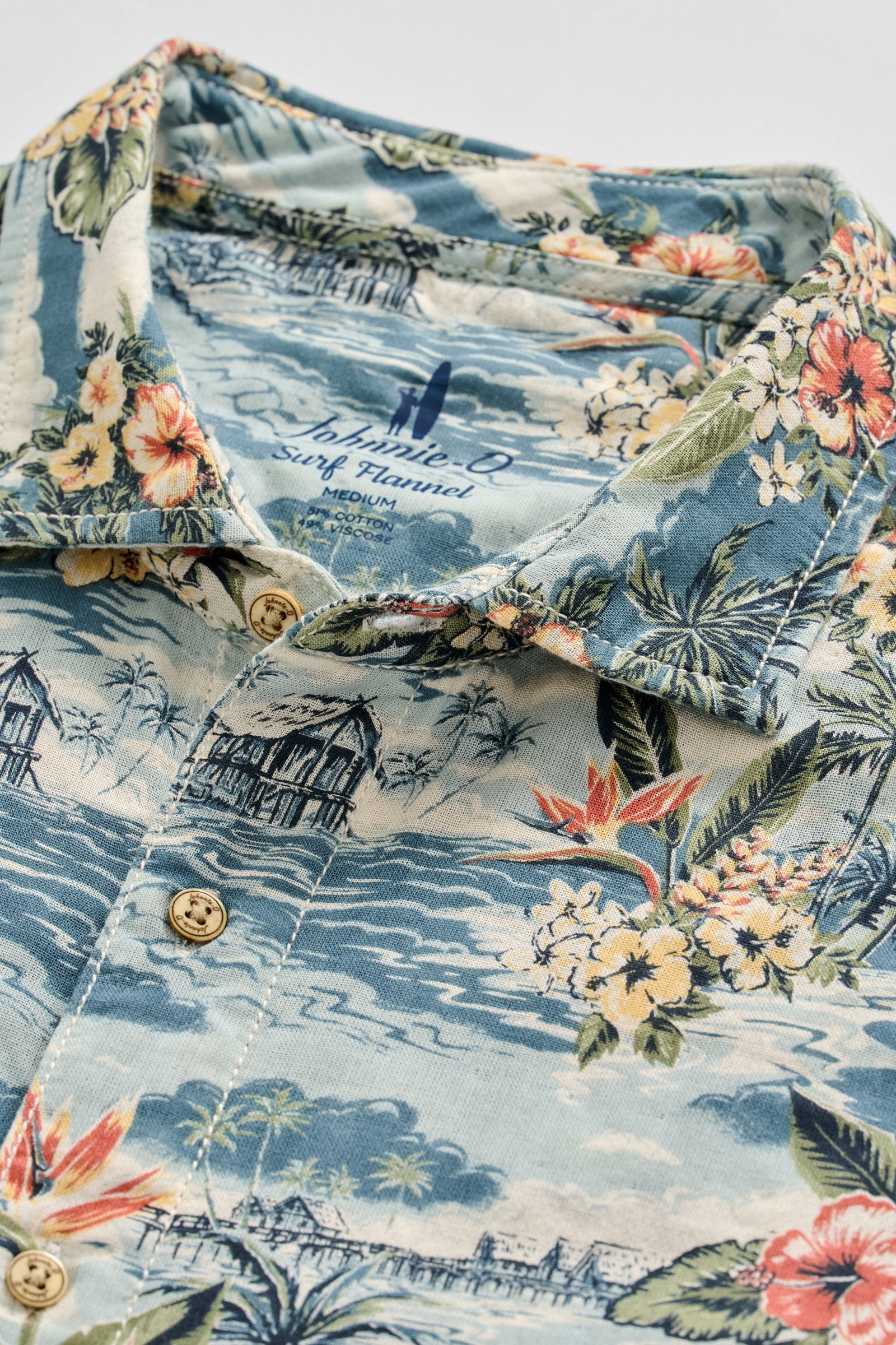 Hawaiian shirt with floral and beach scene design on a light blue background