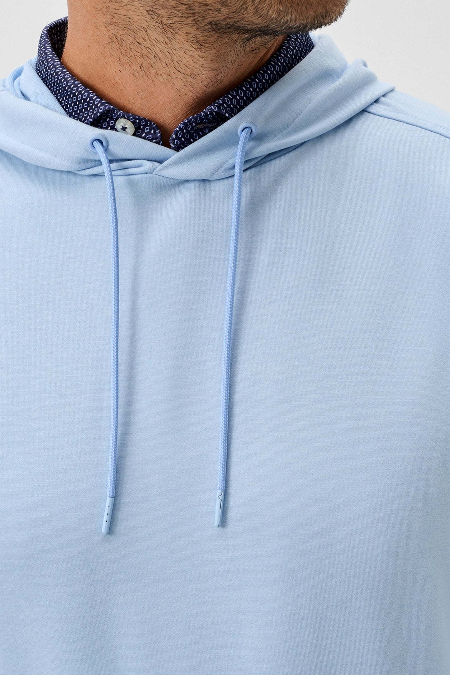 Light blue hoodie with a zipper detail on a neutral background