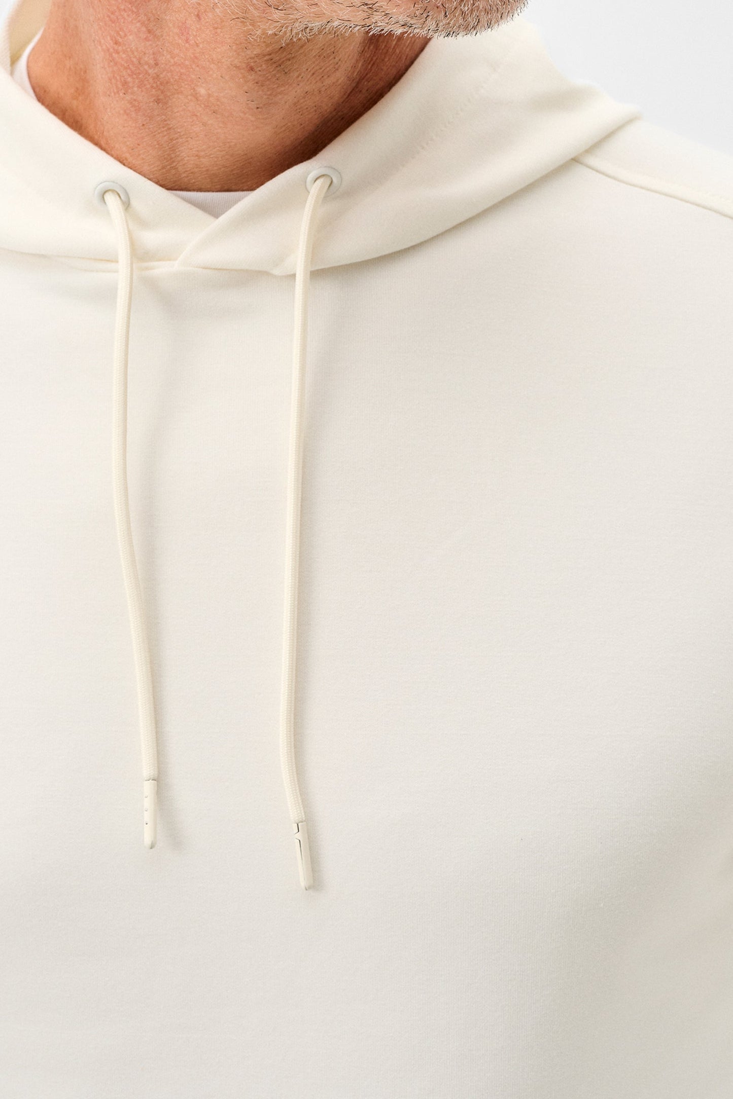 Close-up of a beige hoodie with a focus on the hood and drawstring.