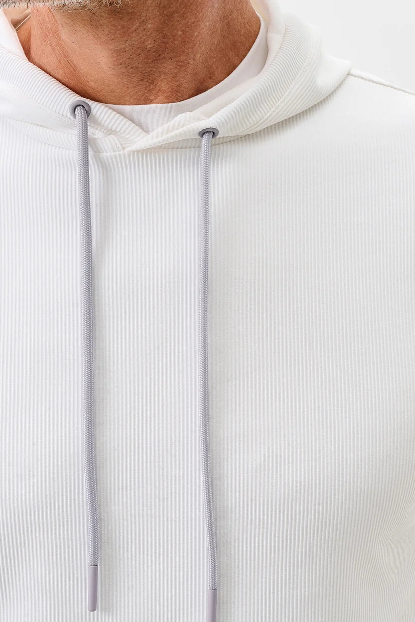 Close-up of a person wearing a white ribbed hoodie with a blurred background