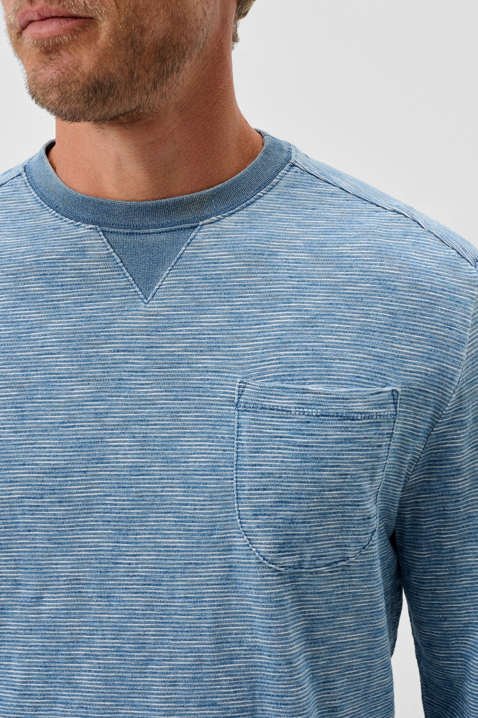 Man wearing a blue striped long-sleeve shirt on a light gray background