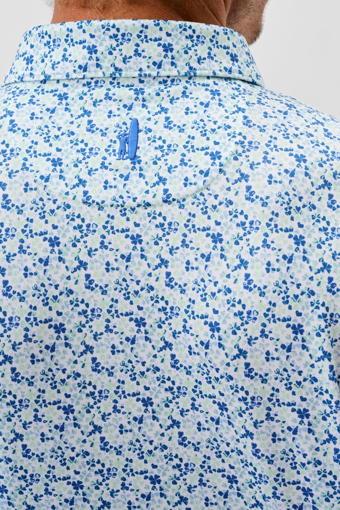 Close-up of a floral-patterned shirt with a brand logo on a plain background
