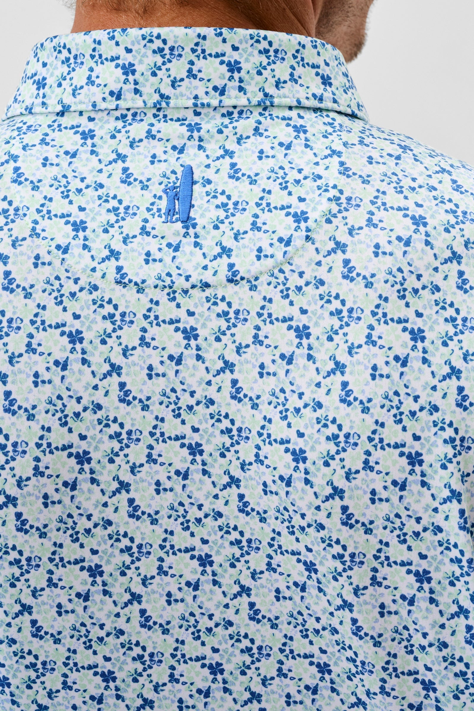 Close-up of a floral-patterned shirt with a brand logo on a plain background