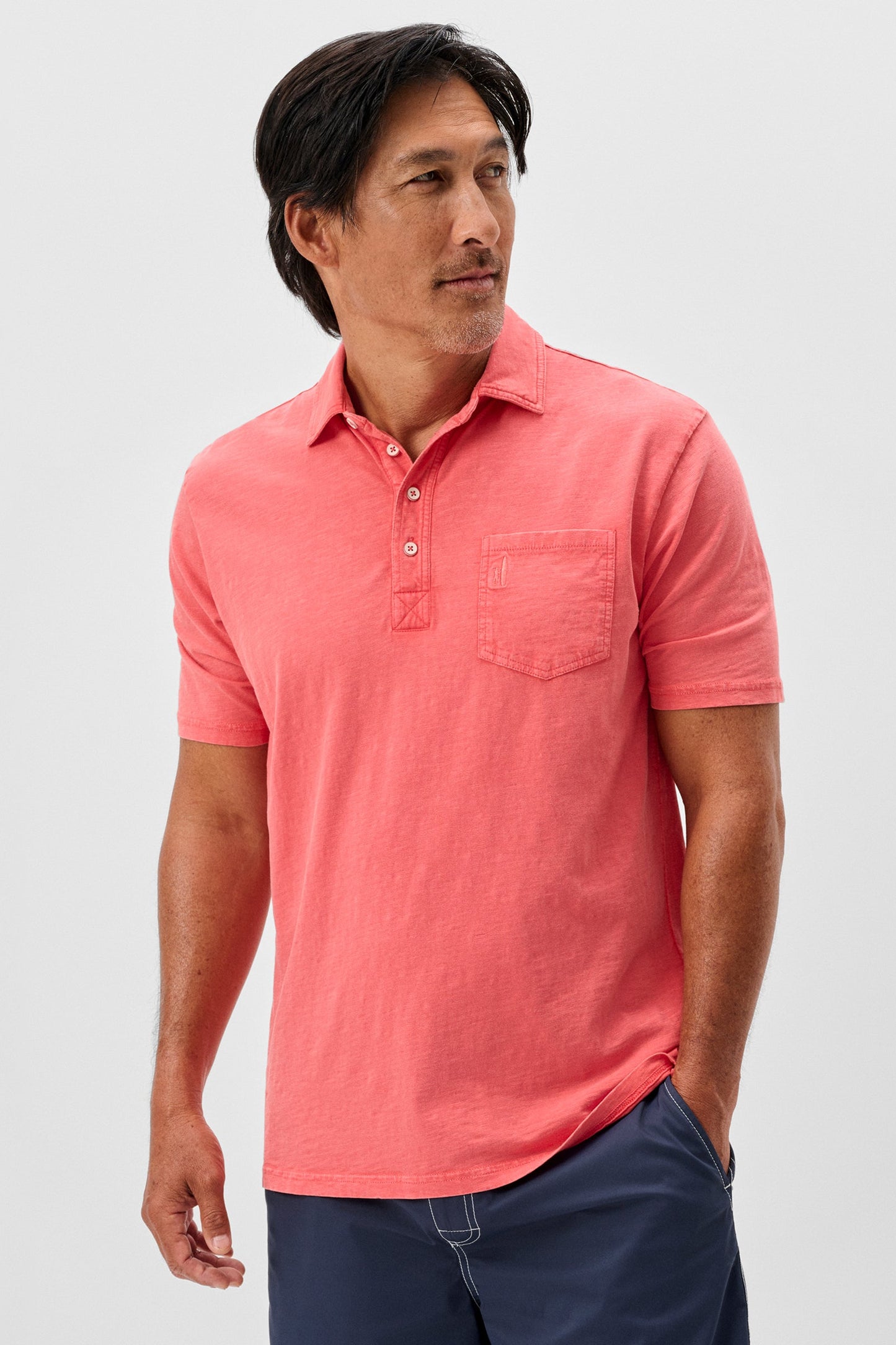 Man wearing a coral polo shirt against a light gray background