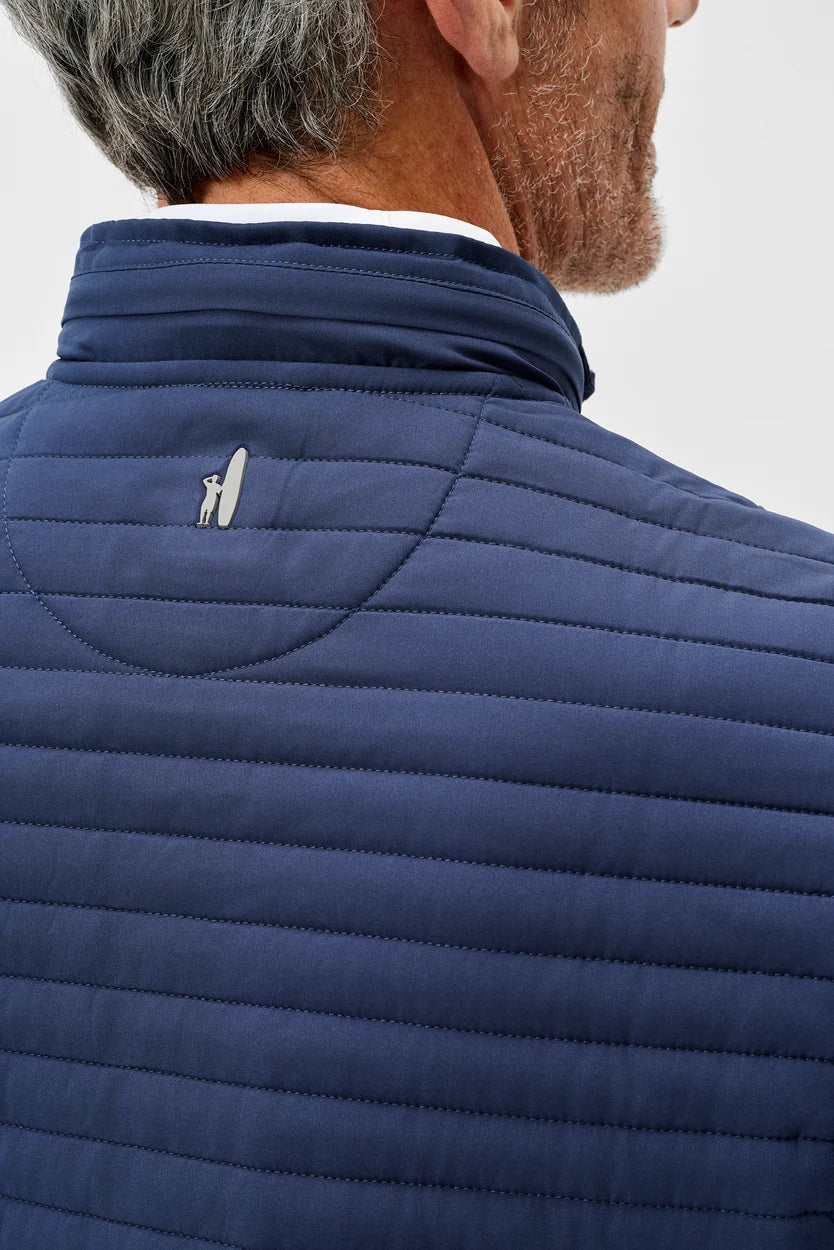 Close-up of a person wearing a blue quilted vest on a light gray background