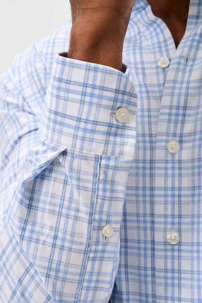 Close-up of a blue and white checkered shirt with buttons.