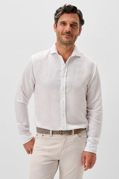 Man wearing a white shirt and light-colored pants against a plain background