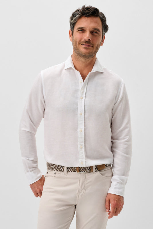 Man wearing a white shirt and light-colored pants against a plain background