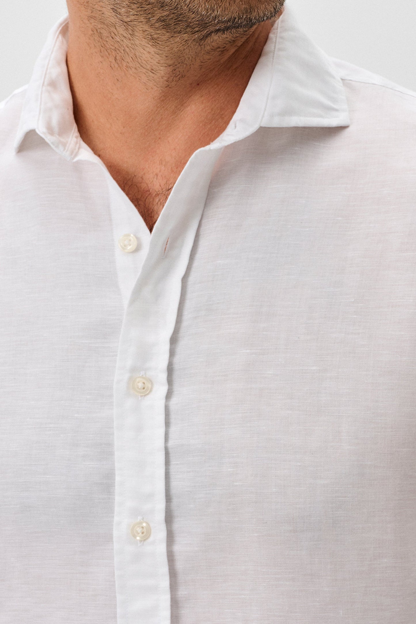 Close-up of a man wearing a white button-up shirt against a light gray background