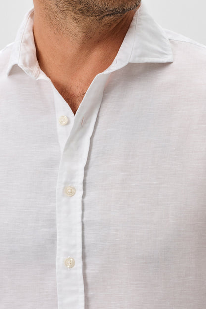 Close-up of a man wearing a white button-up shirt against a light gray background