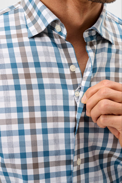 Close-up of a man wearing a long-sleeve button-down shirt with a blue, white, and brown gingham check pattern. His hand is adjusting the collar and buttons.