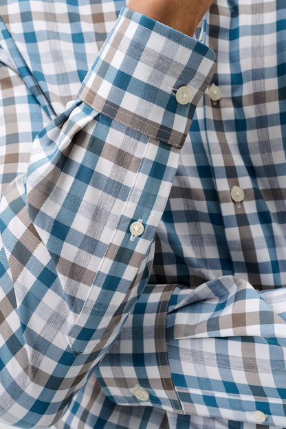 Close-up of a men's long-sleeve button-down shirt with a blue, white, and brown gingham check pattern, showing the cuff and buttons.