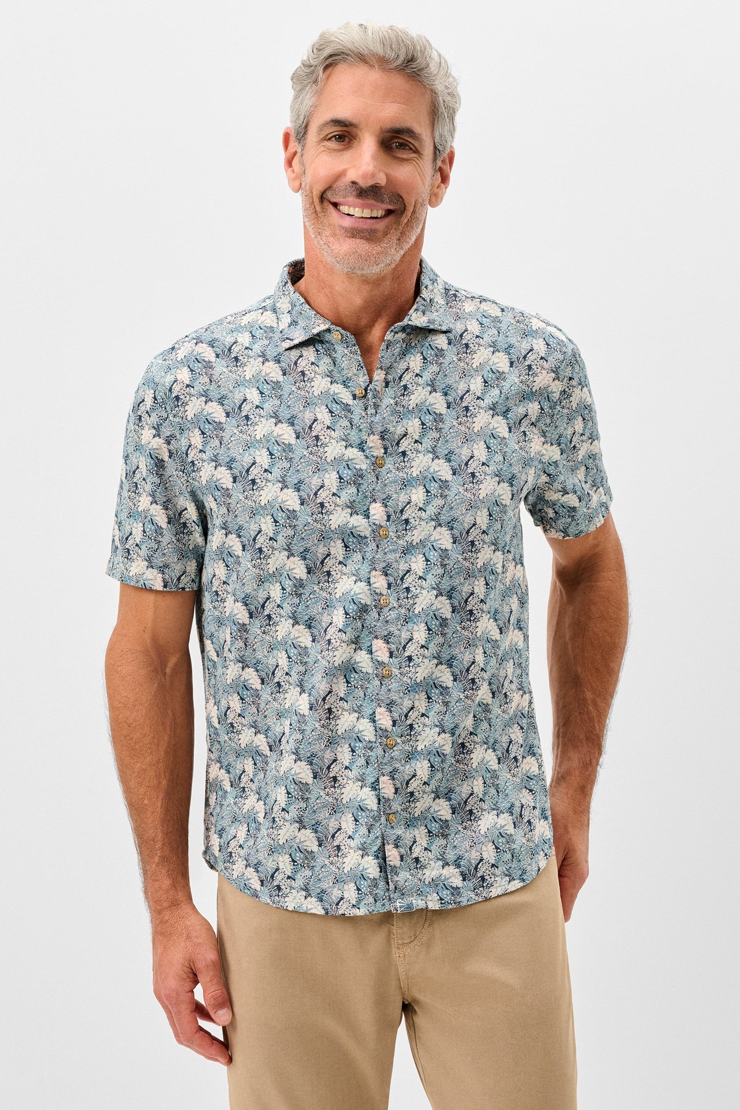Man wearing a floral short-sleeve shirt on a light gray background