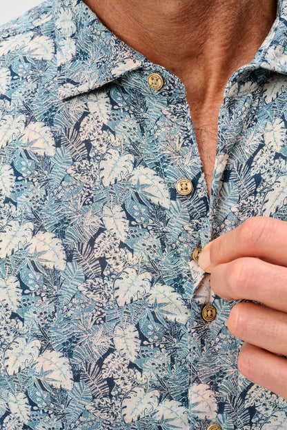 Close-up of a person wearing a blue floral shirt with a button being adjusted.
