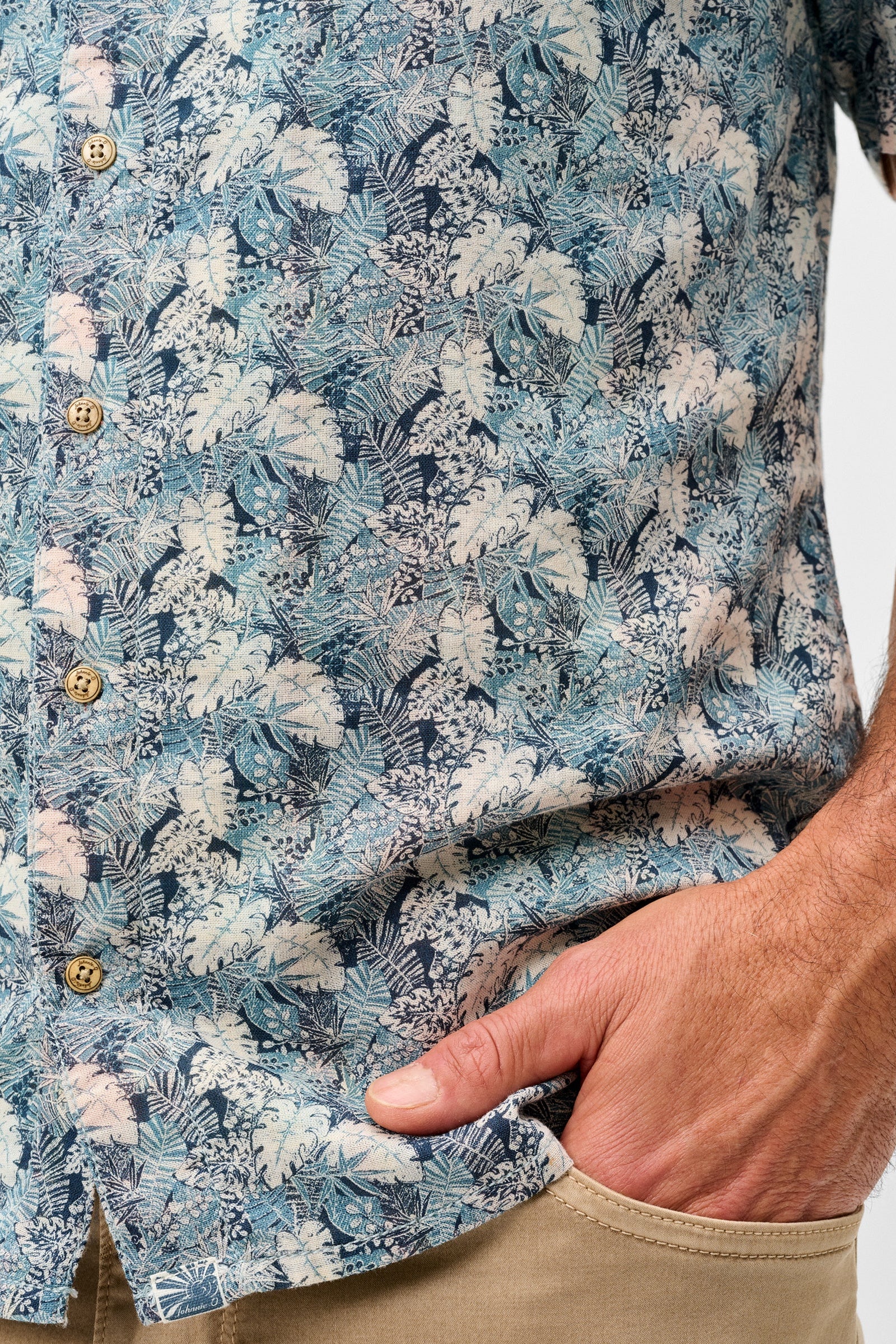 Close-up of a person wearing a blue floral patterned shirt with beige pants.