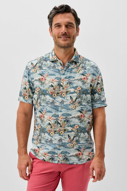 Man wearing a floral patterned shirt and pink pants on a white background