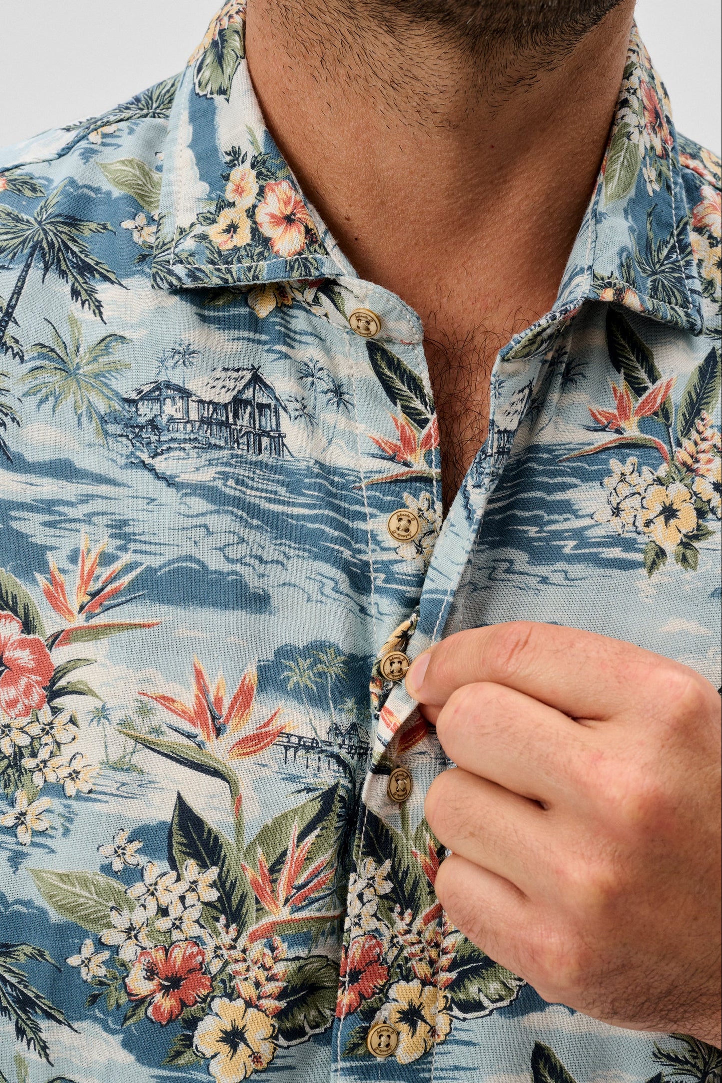 Close-up of a person wearing a tropical floral patterned shirt.