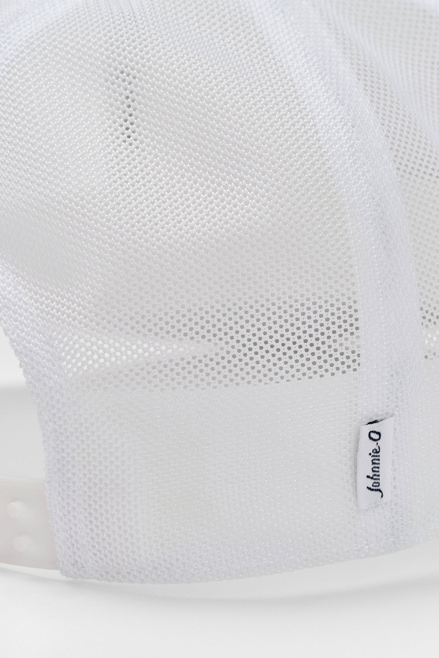 Close-up of a white sneaker with mesh design and brand logo on a light gray background