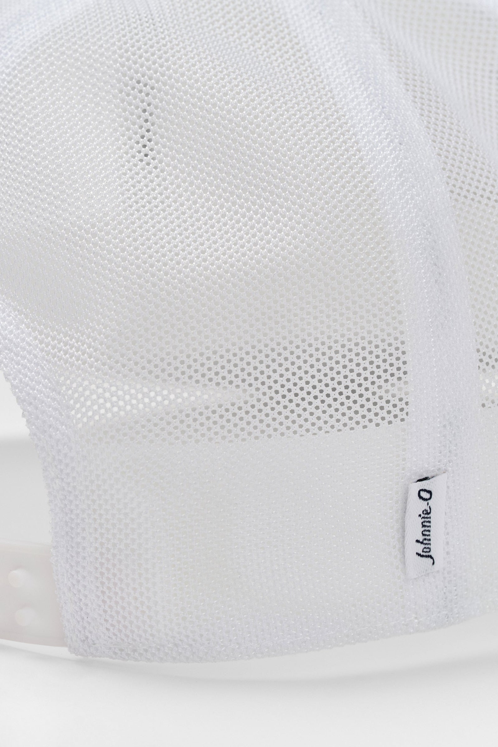 Close-up of a white sneaker with mesh design and brand logo on a light gray background