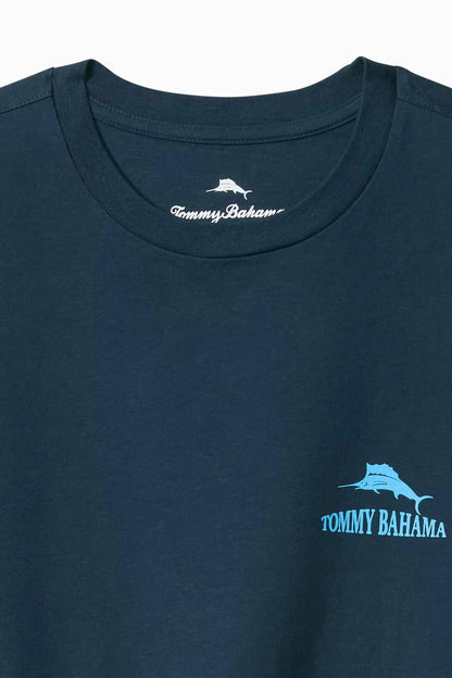 Close-up of a dark navy blue Tommy Bahama t-shirt featuring a light blue marlin graphic and brand name on the left chest, with the white Tommy Bahama neck label visible inside the collar.