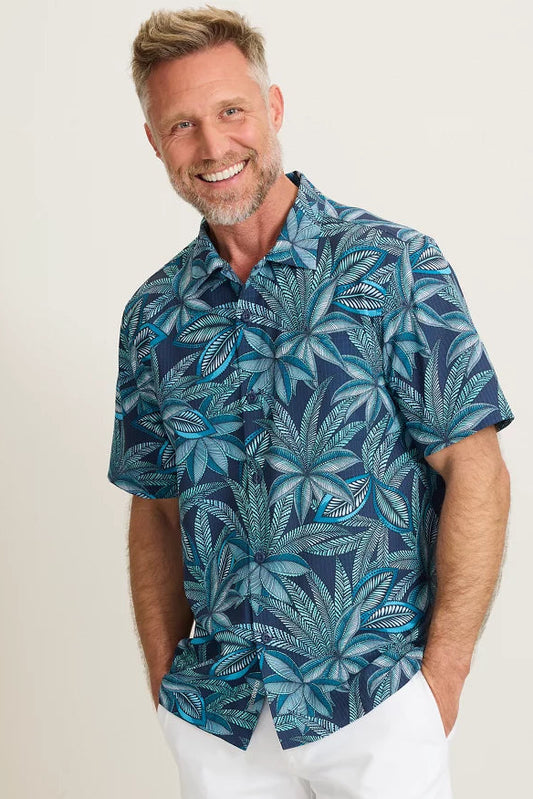 Man wearing a blue leaf-patterned shirt against a white background