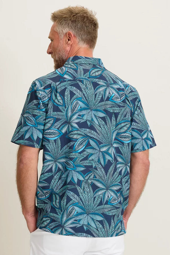 Man wearing a blue leaf patterned shirt against a white background