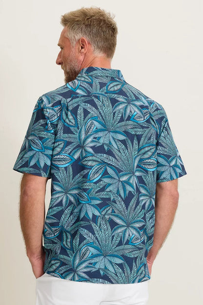 Man wearing a blue leaf patterned shirt against a white background