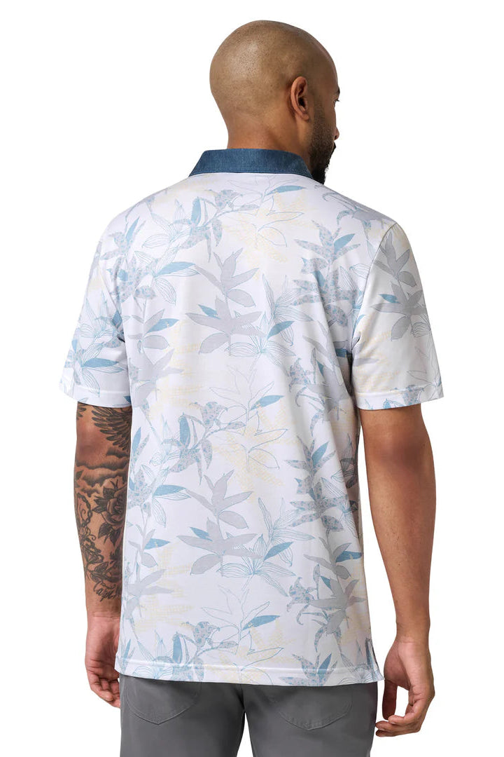 Man wearing a white polo shirt with blue floral pattern on a white background